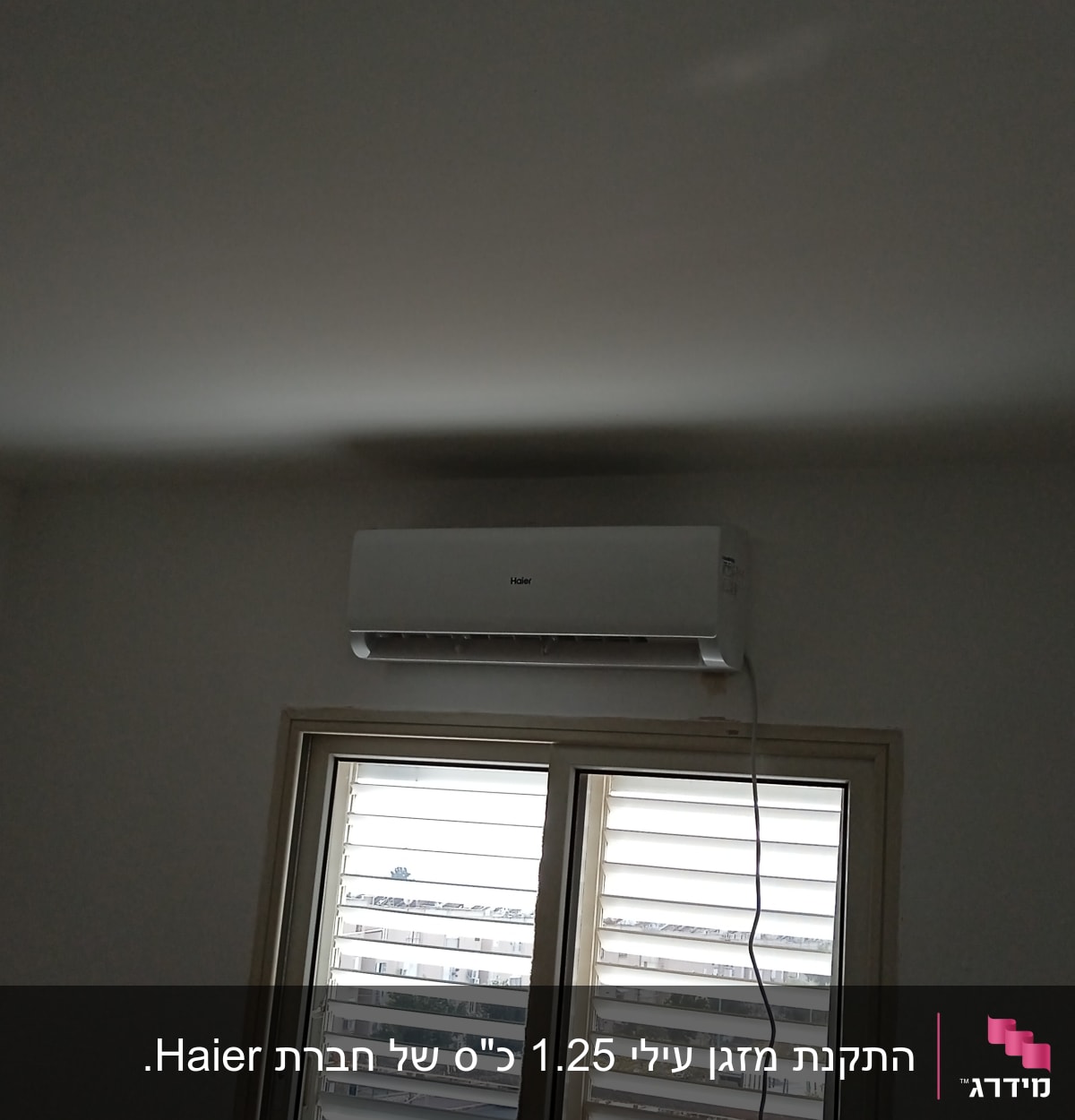 מזגן מותקן על קיר מעל חלון עם תריסים